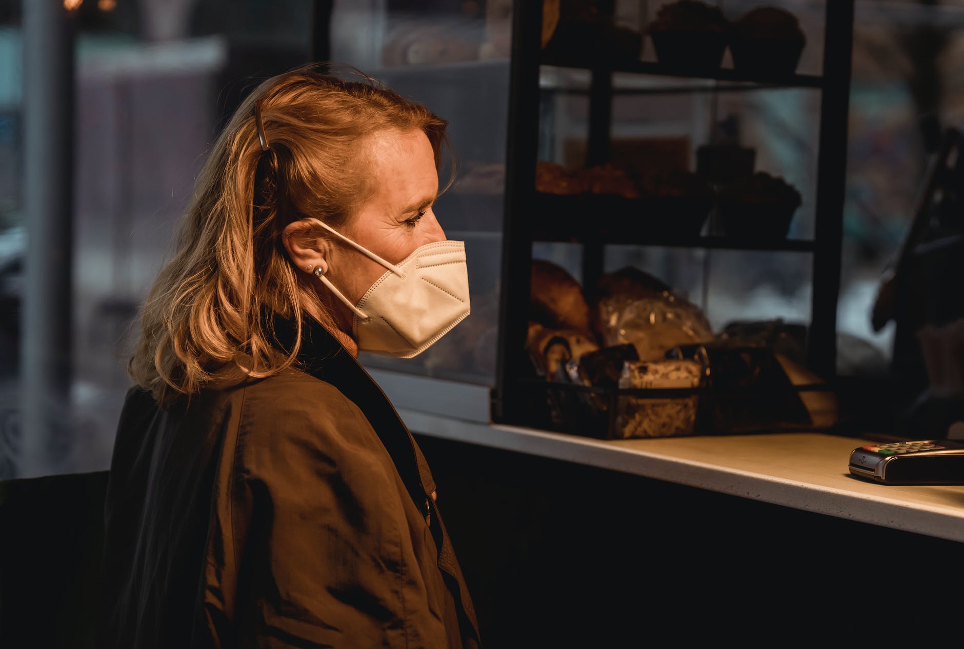 customer in respiratory mask against bakery counter