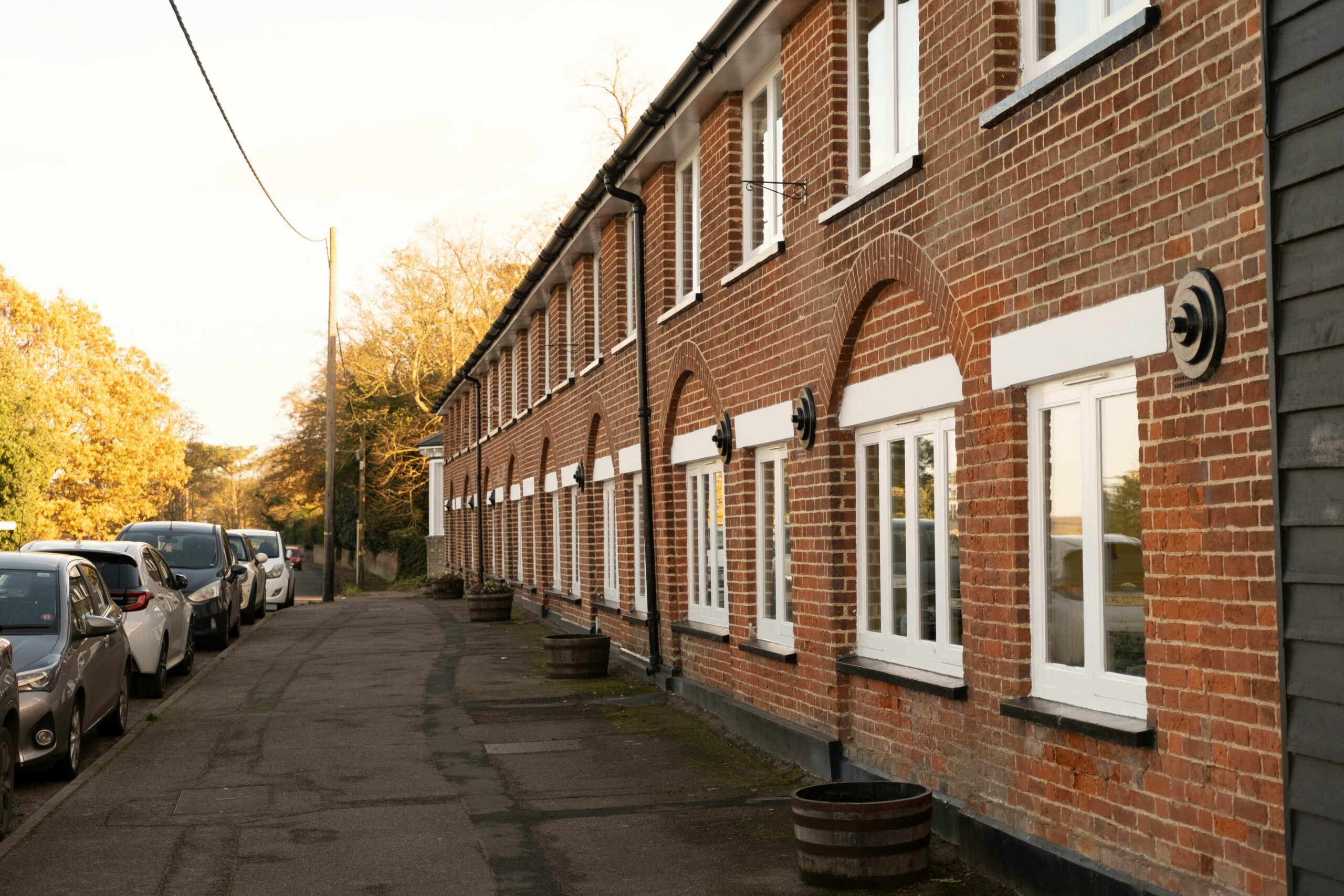 A brick low rise apartment building with cars parked along the street