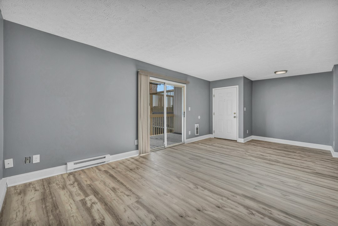 Empty apartment living room with a sliding glass door to a balcony (illustrative stock photo)