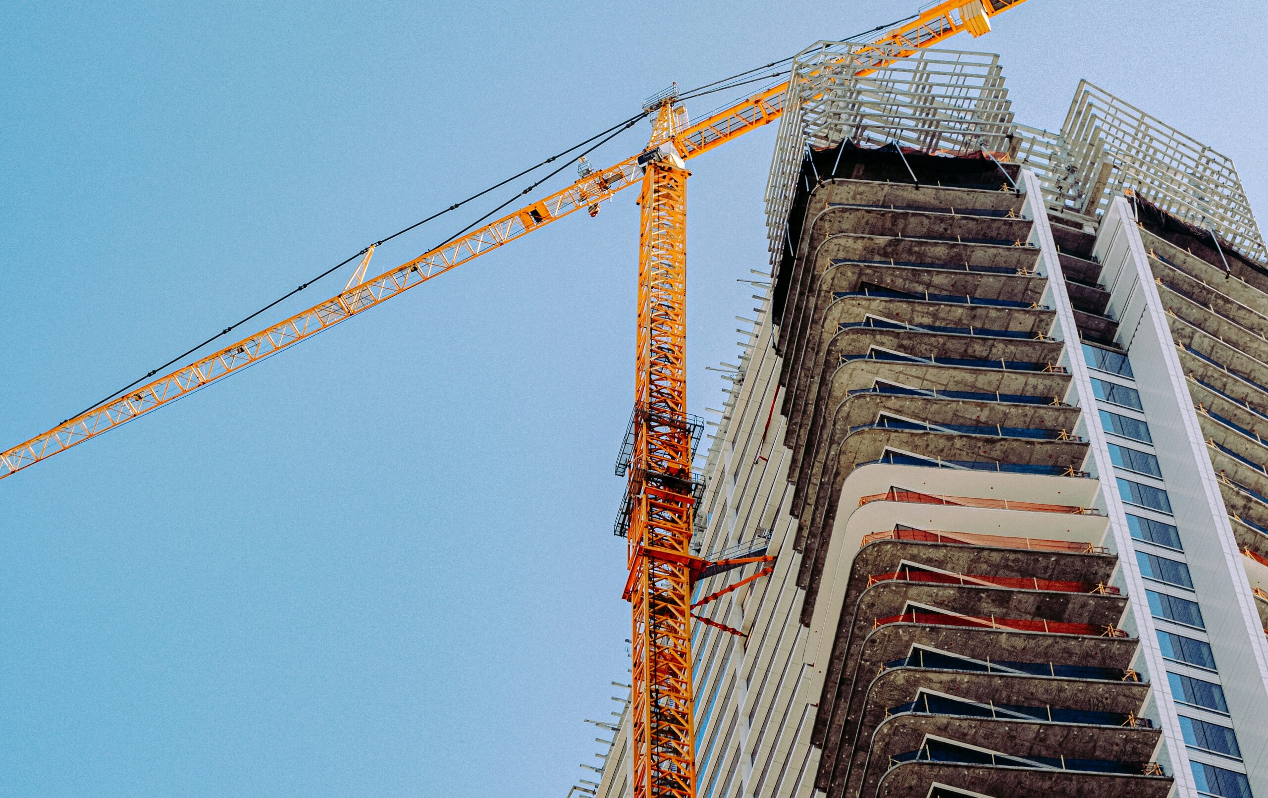 A residential apartment tower under construction, its concrete frame partly clad