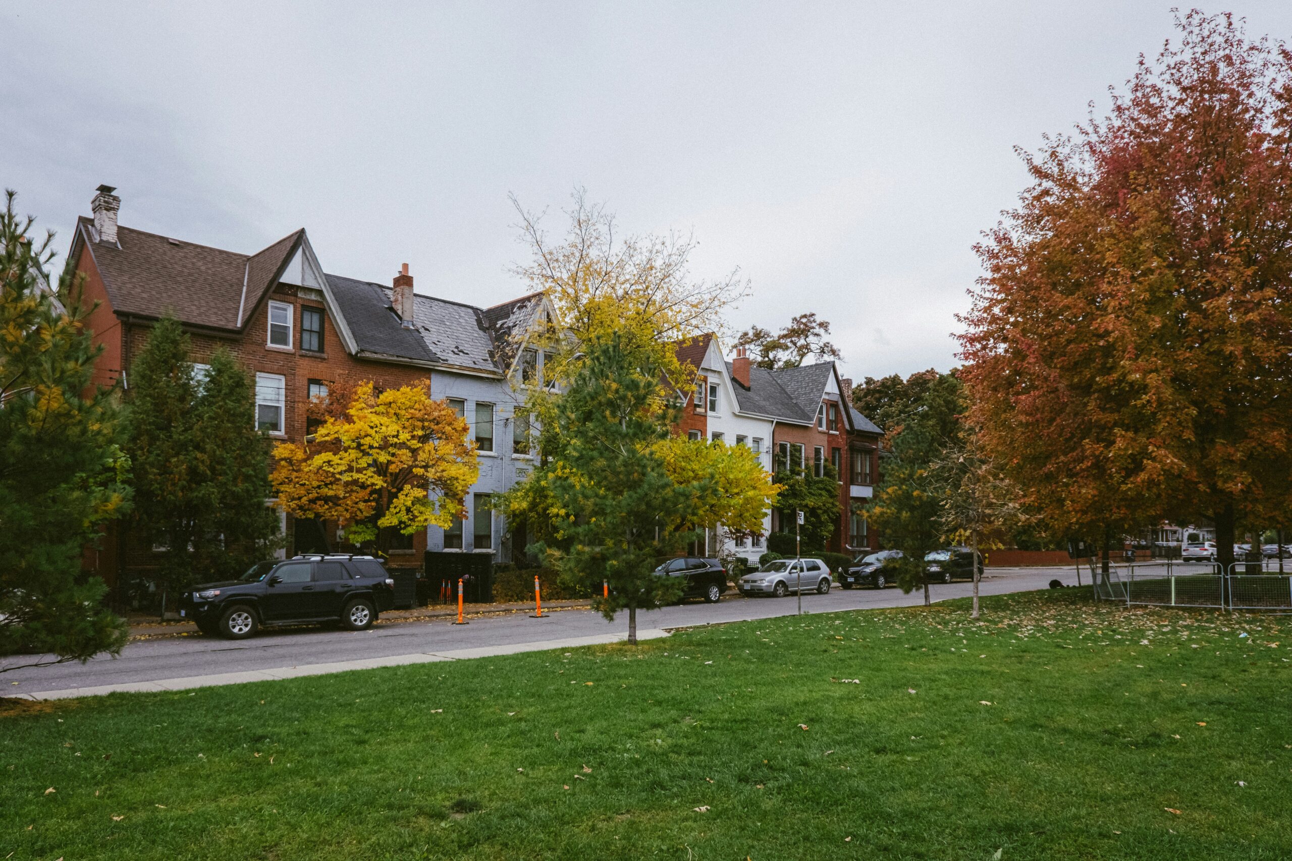 A residential street lined with houses and parked cars
