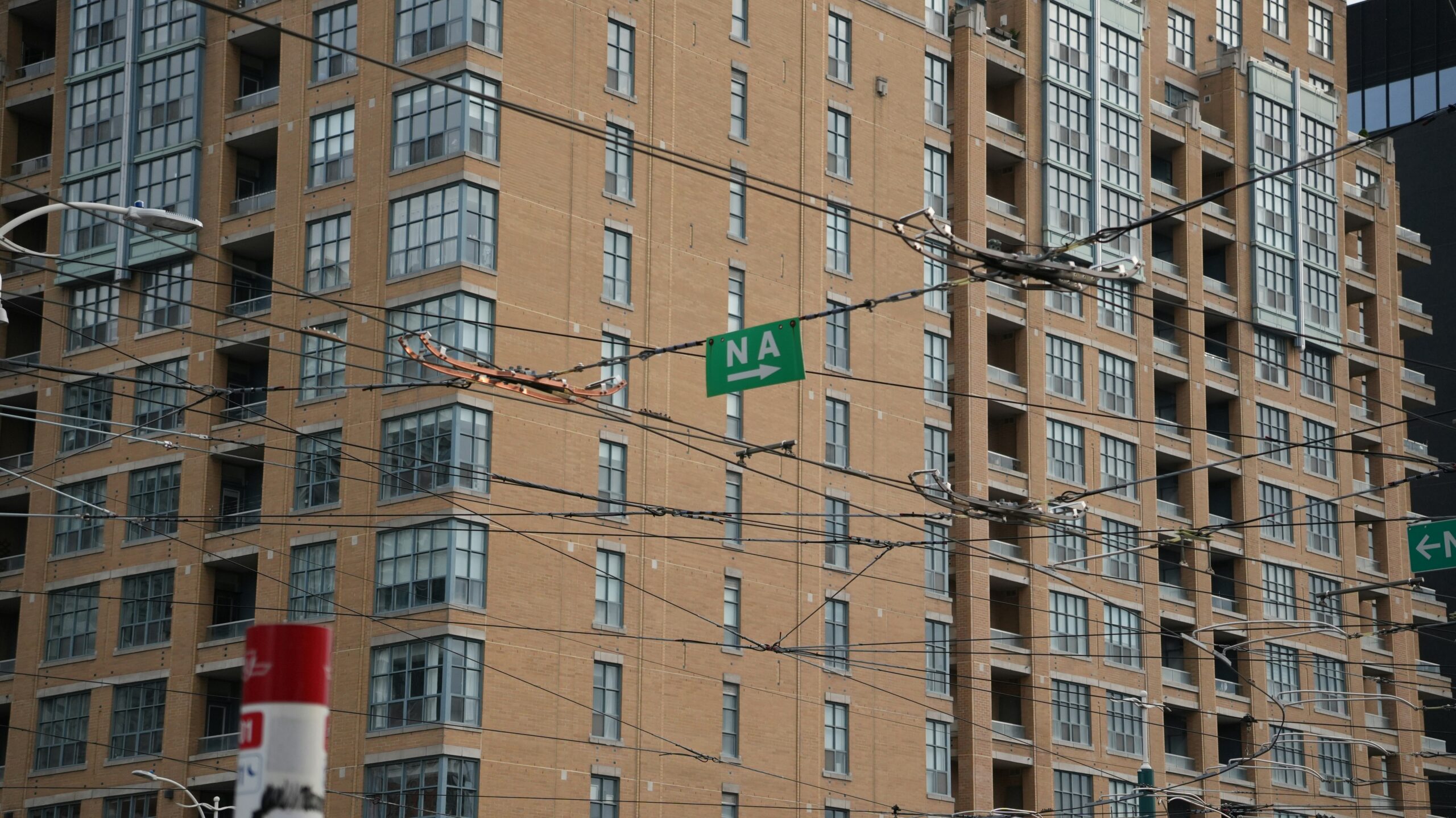 A Toronto residential facade seen through overhead streetcar wires