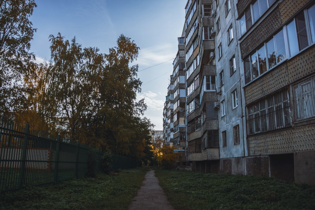 Apartment building with trees and a sidewalk, illustrative stock photo