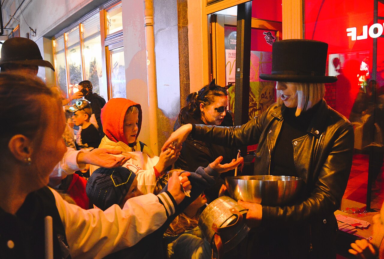 Children in Halloween costumes reaching into a candy bowl while trick-or-treating