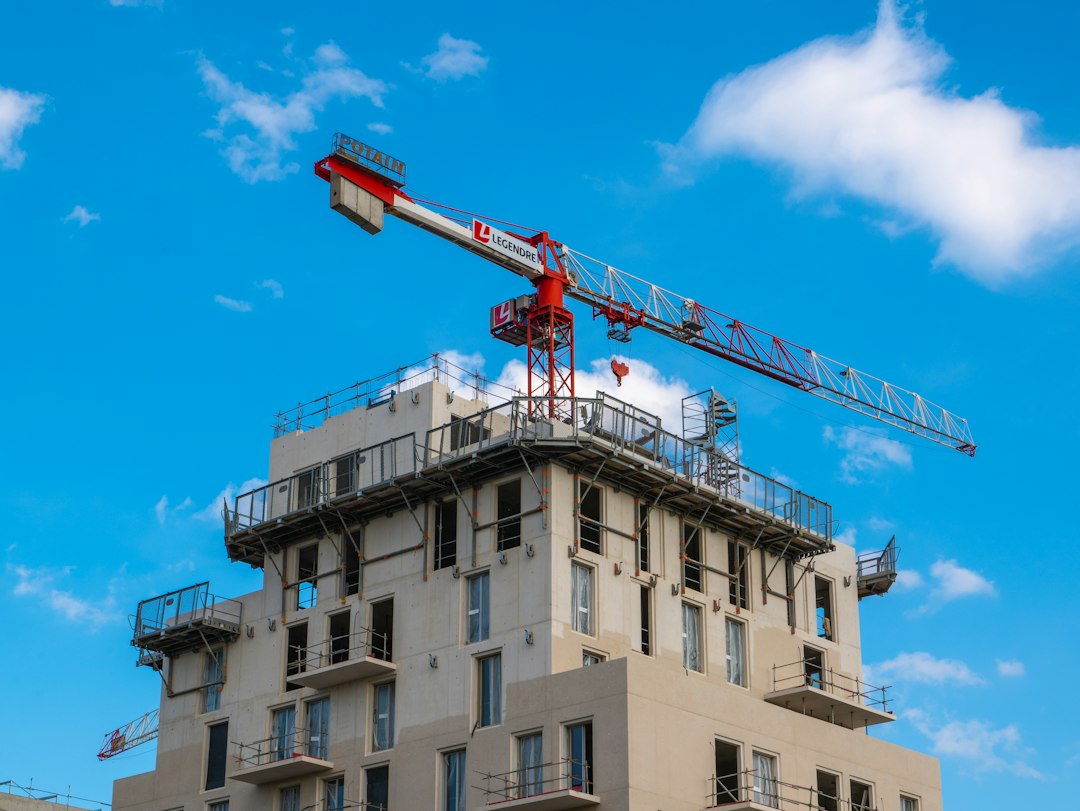Crane behind a building under construction against a blue sky (stock photo, not a specific project)