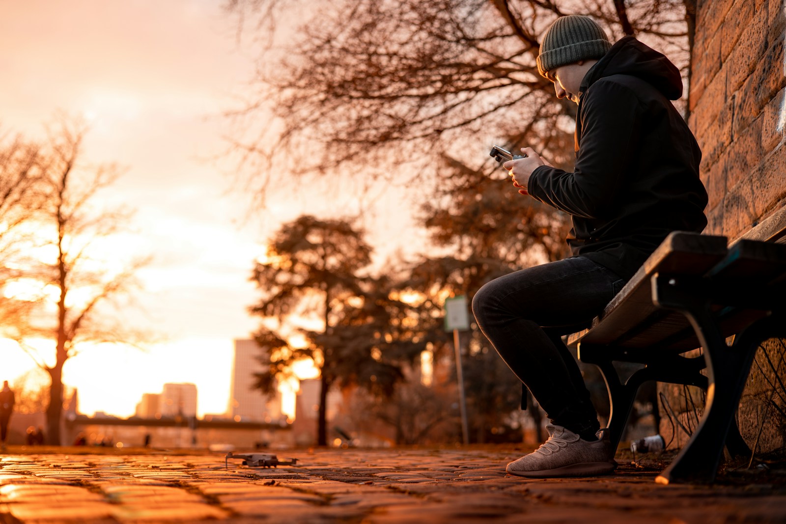 Silhouette of a drone pilot on a bench at golden hour