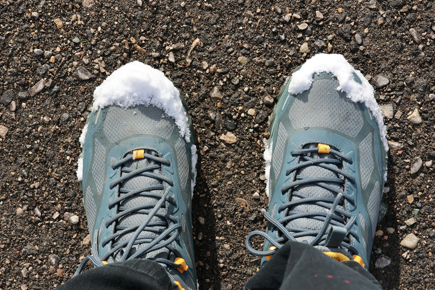 Hiking shoes with a dusting of snow on a gravel trail