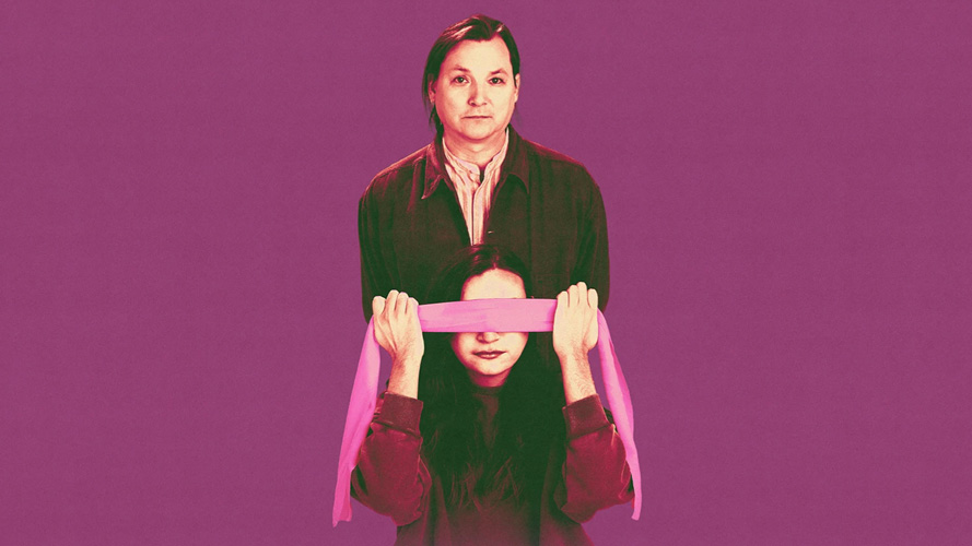 Promotional image for Ka Uinaksheshet: a man stands behind a young woman holding a pink blindfold over her eyes