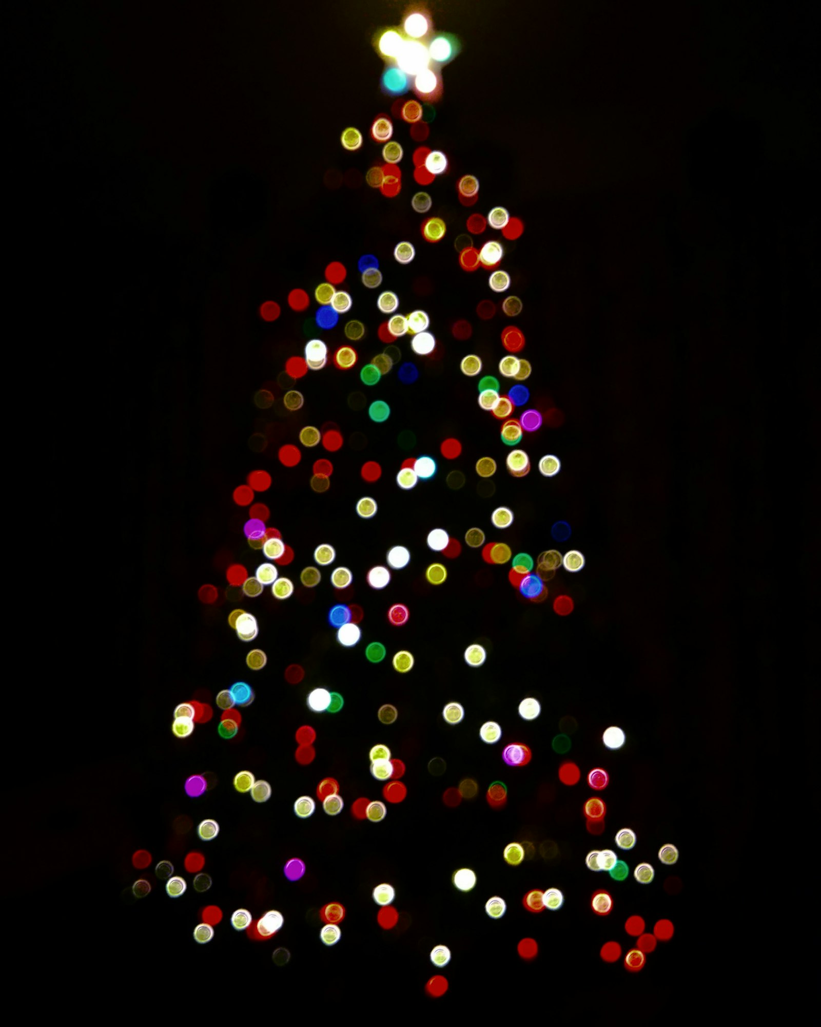 Christmas tree glowing with multicoloured lights at night