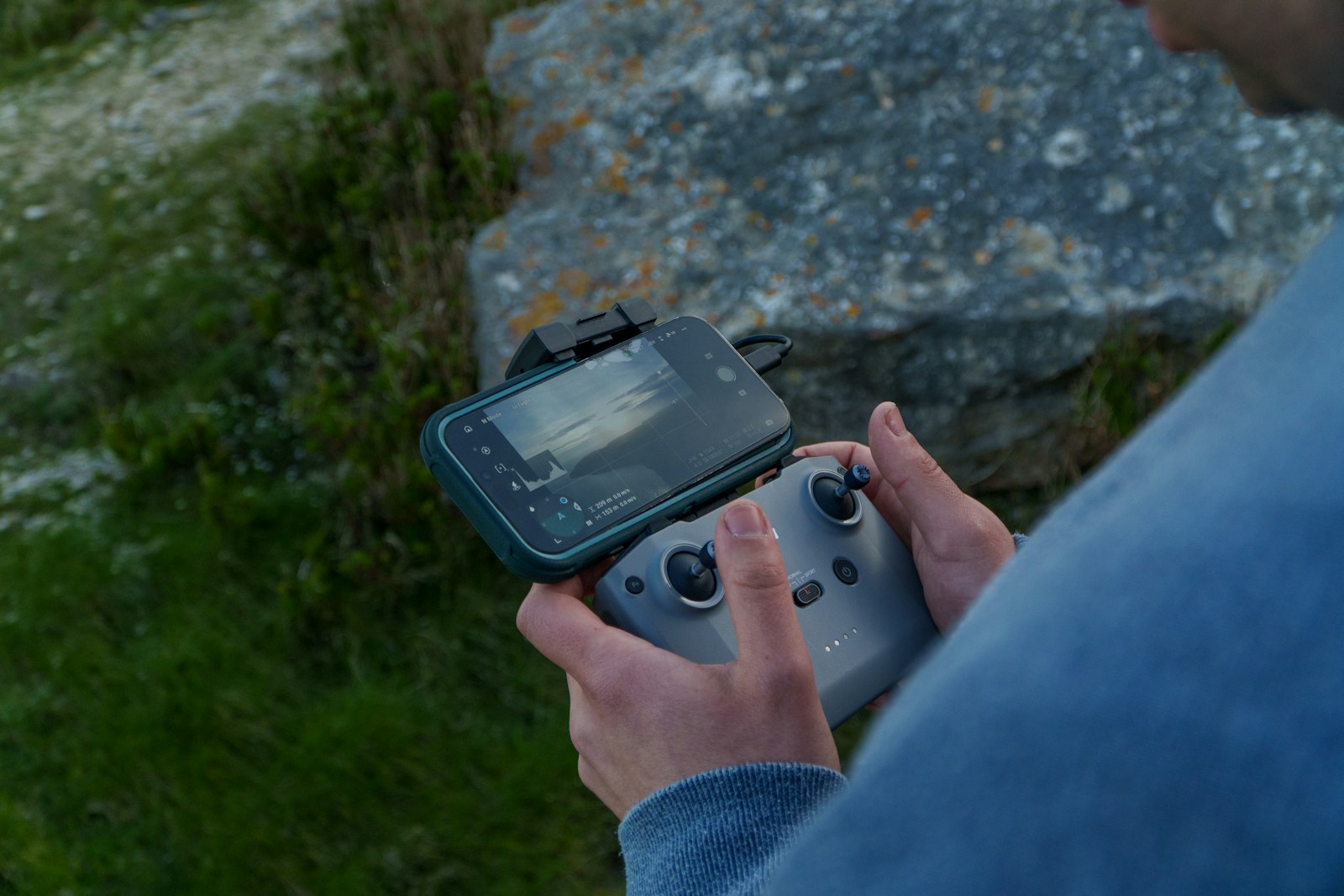 Person holding a drone controller with a built-in screen