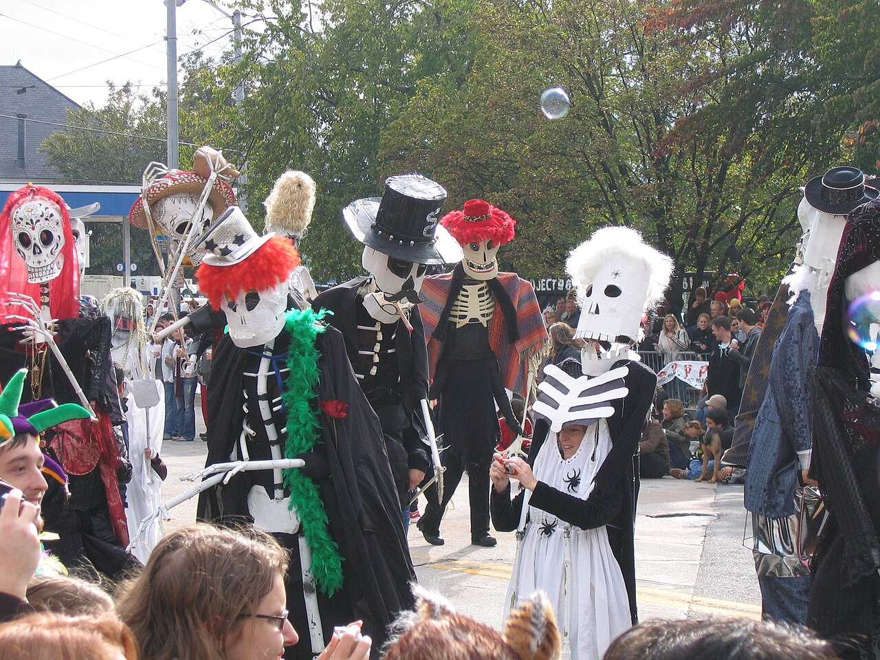 Group in matching skeleton costumes and skull masks at a Halloween parade