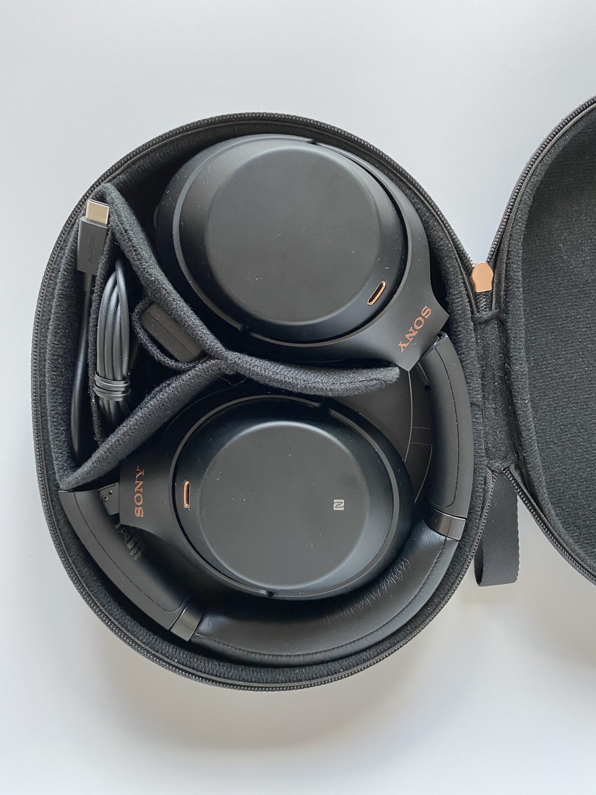 Sony WH-1000XM3 noise-cancelling headphones folded in their carrying case with a USB cable