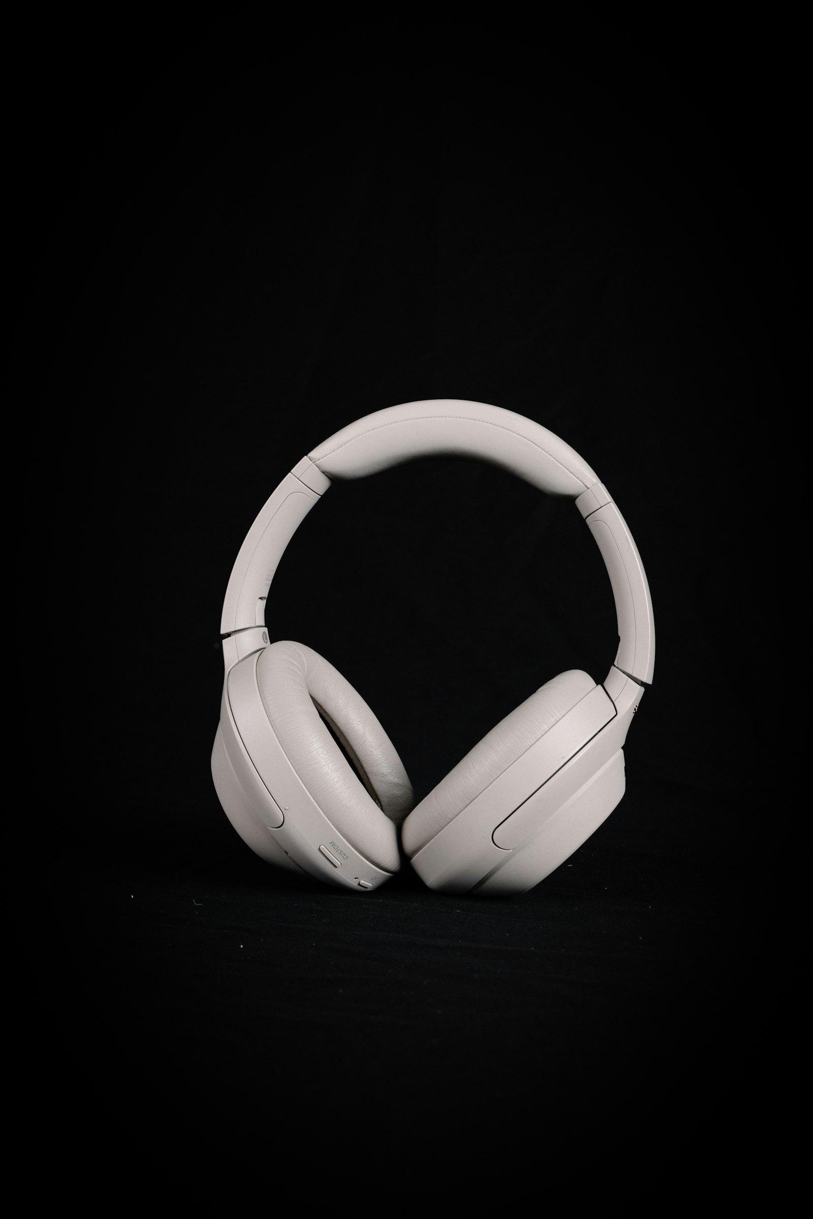 Silver-grey Sony over-ear noise-cancelling headphones standing on a dark background