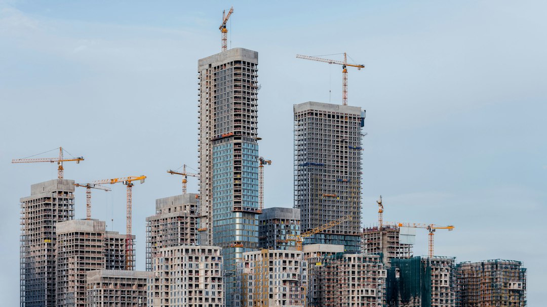 Towers under construction with cranes against the sky