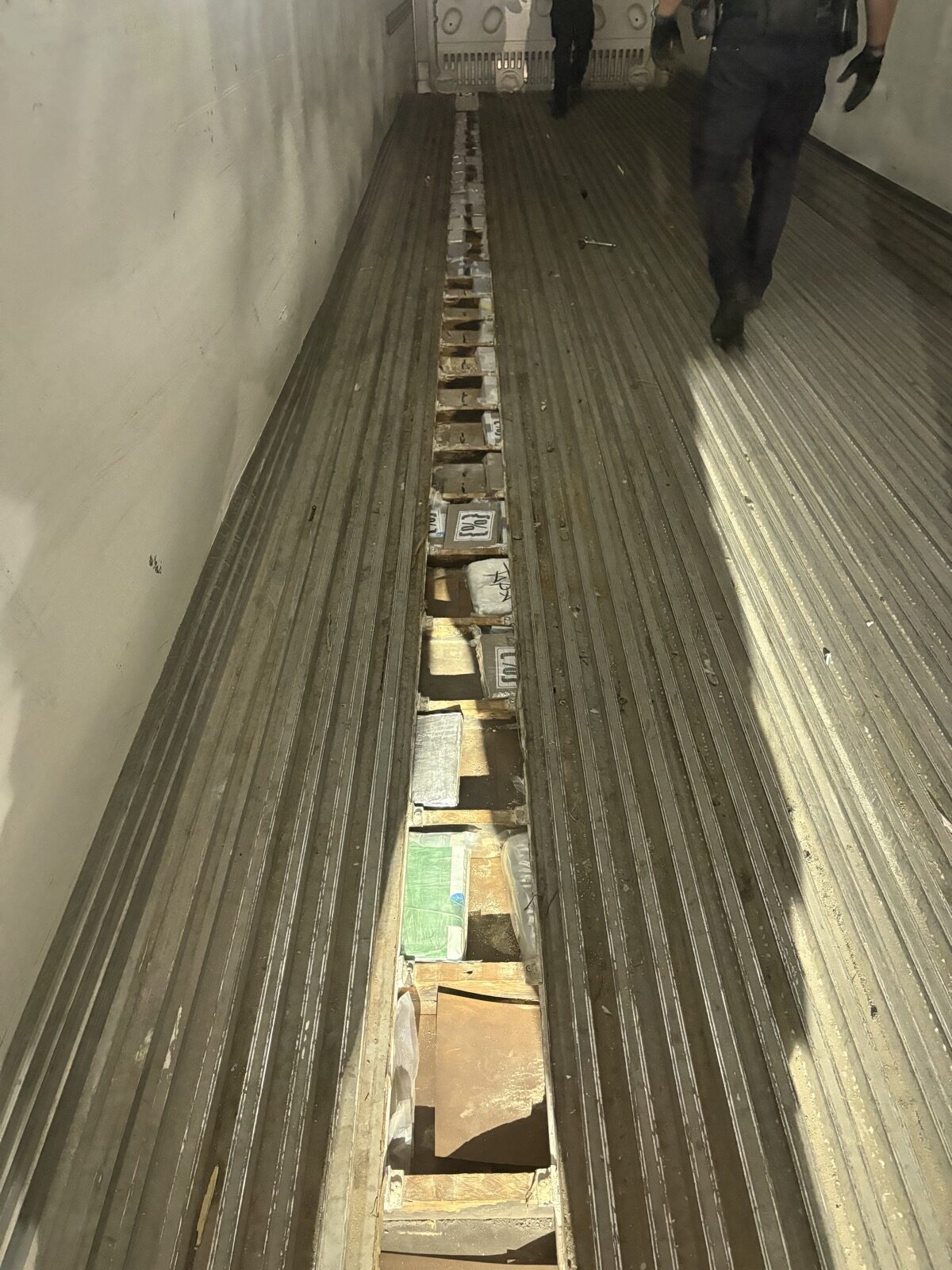 Packages hidden in an opened compartment running along the floor of a truck trailer