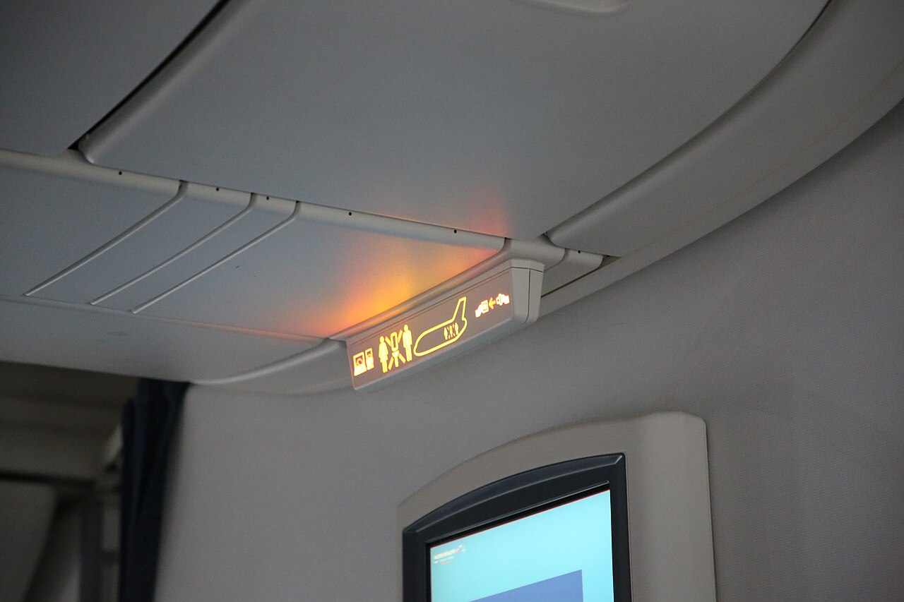 Closed overhead storage bins above the seats in a wide-body airliner cabin
