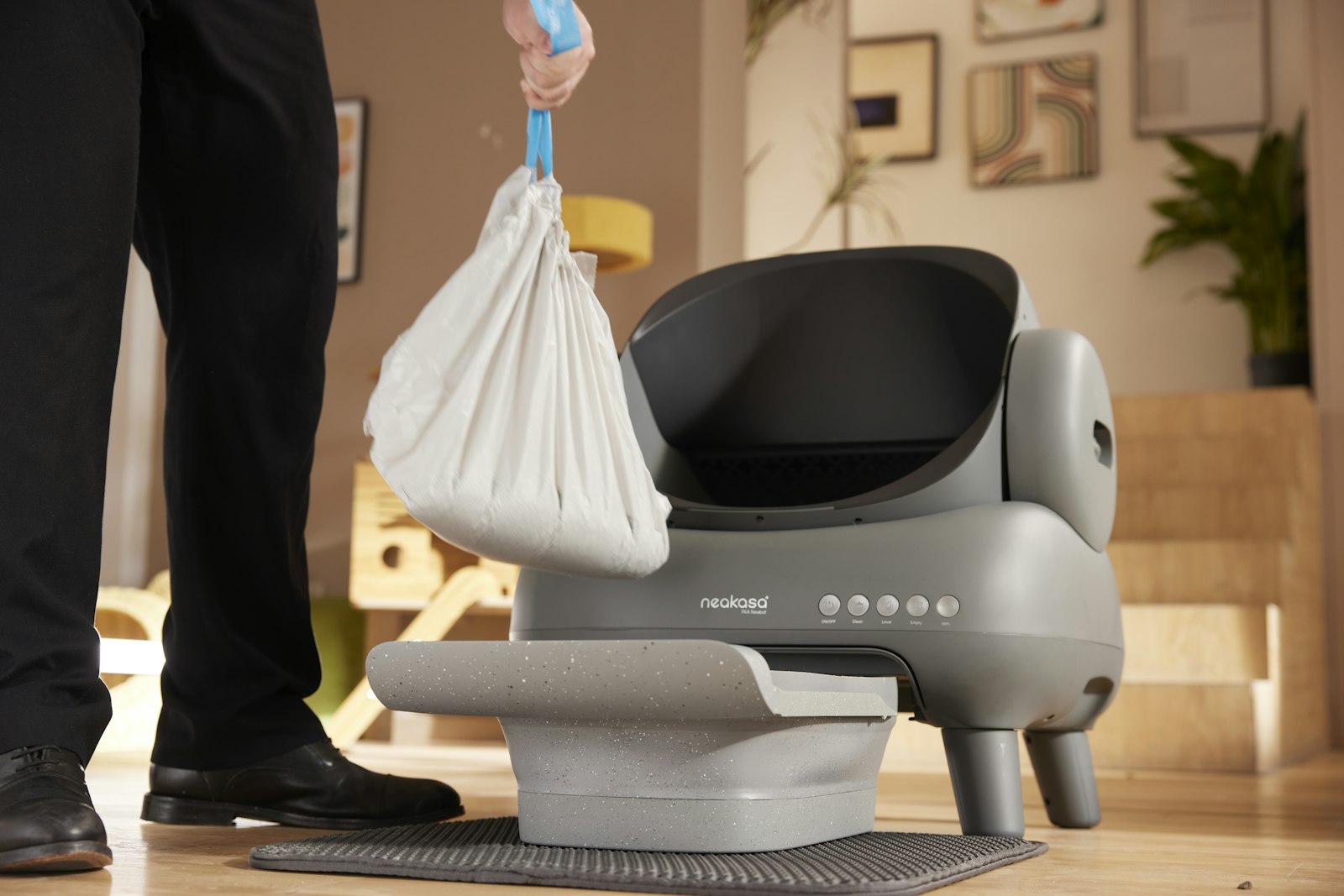 Person lifting a tied waste bag away from the removable waste drawer of a Neakasa automatic litter box