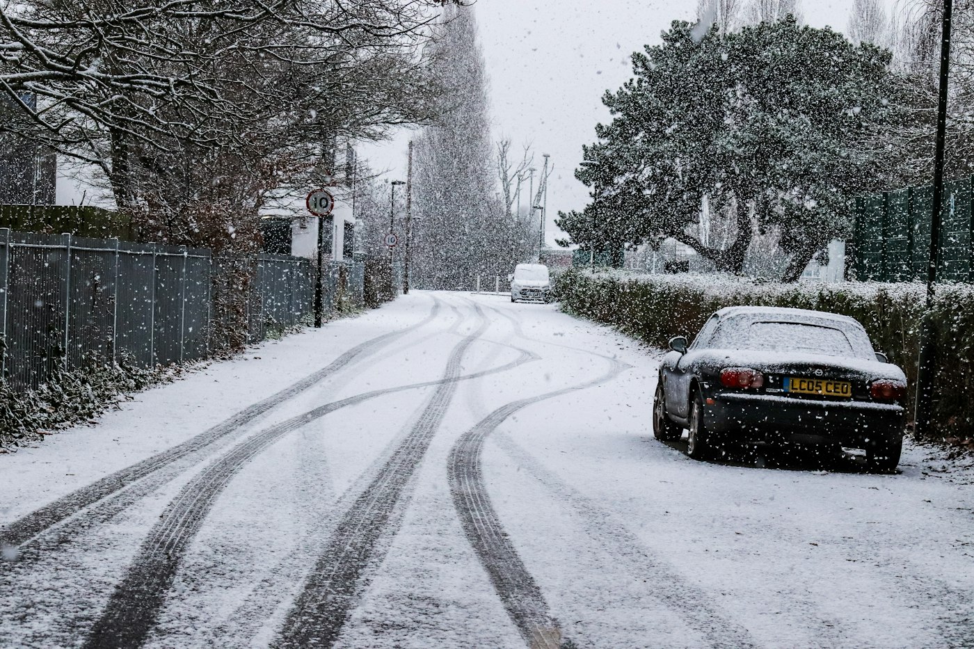 A car on a road in heavy snowfall, leaving tire tracks