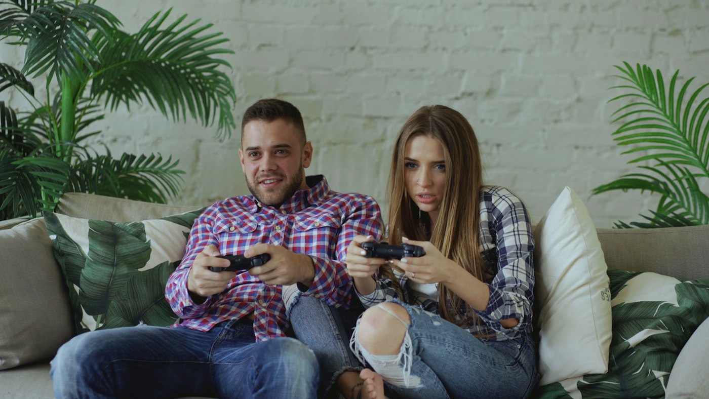 Couple playing console games on a couch in a living room