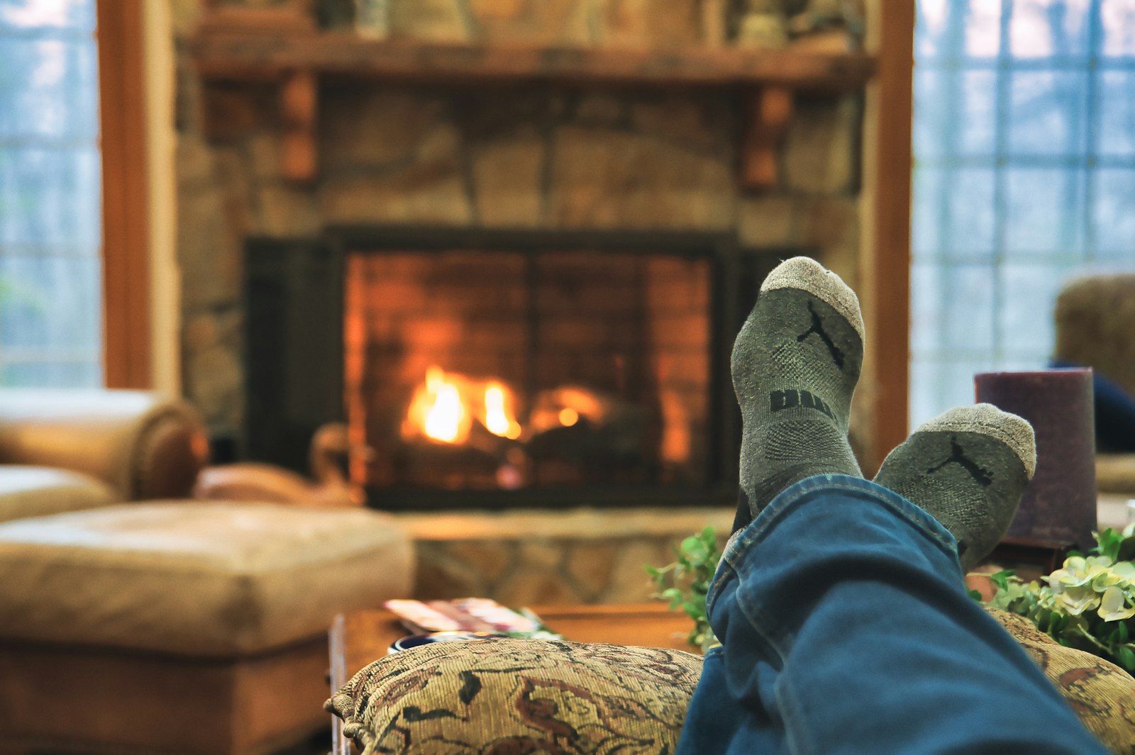 Feet in wool socks stretched toward a stone fireplace