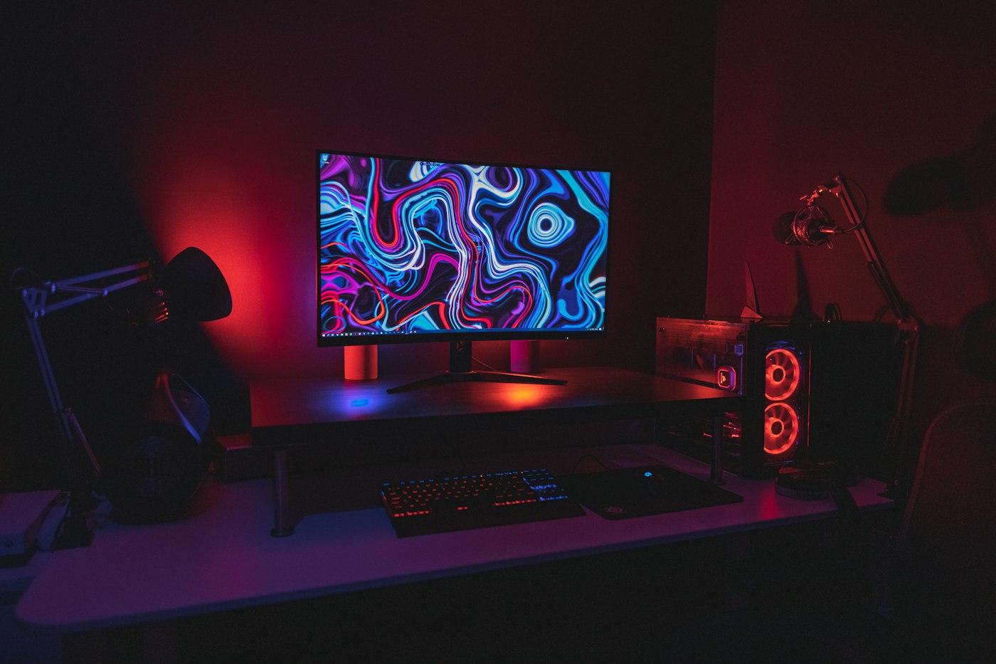 Gaming monitor and keyboard on a desk lit in red
