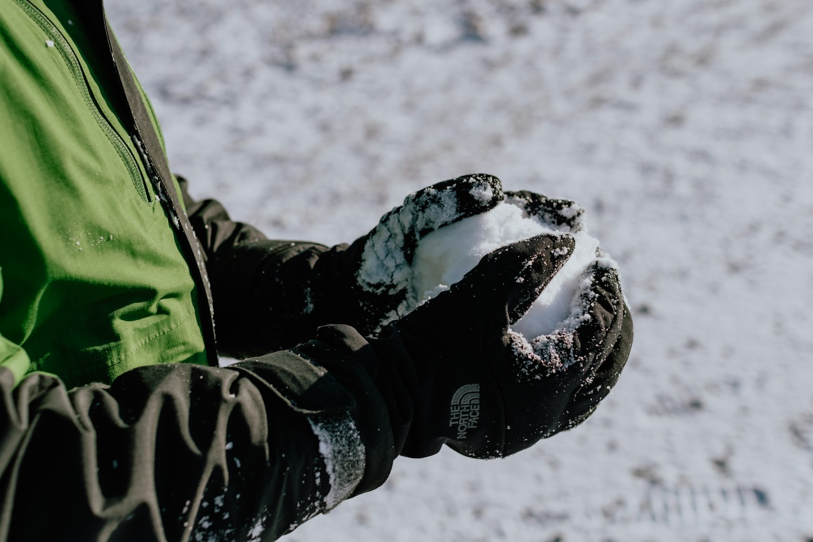 Gloved hands packing a snowball