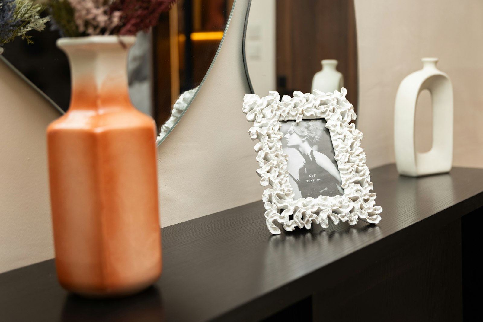 White photo frame on a shelf beside ceramic vases