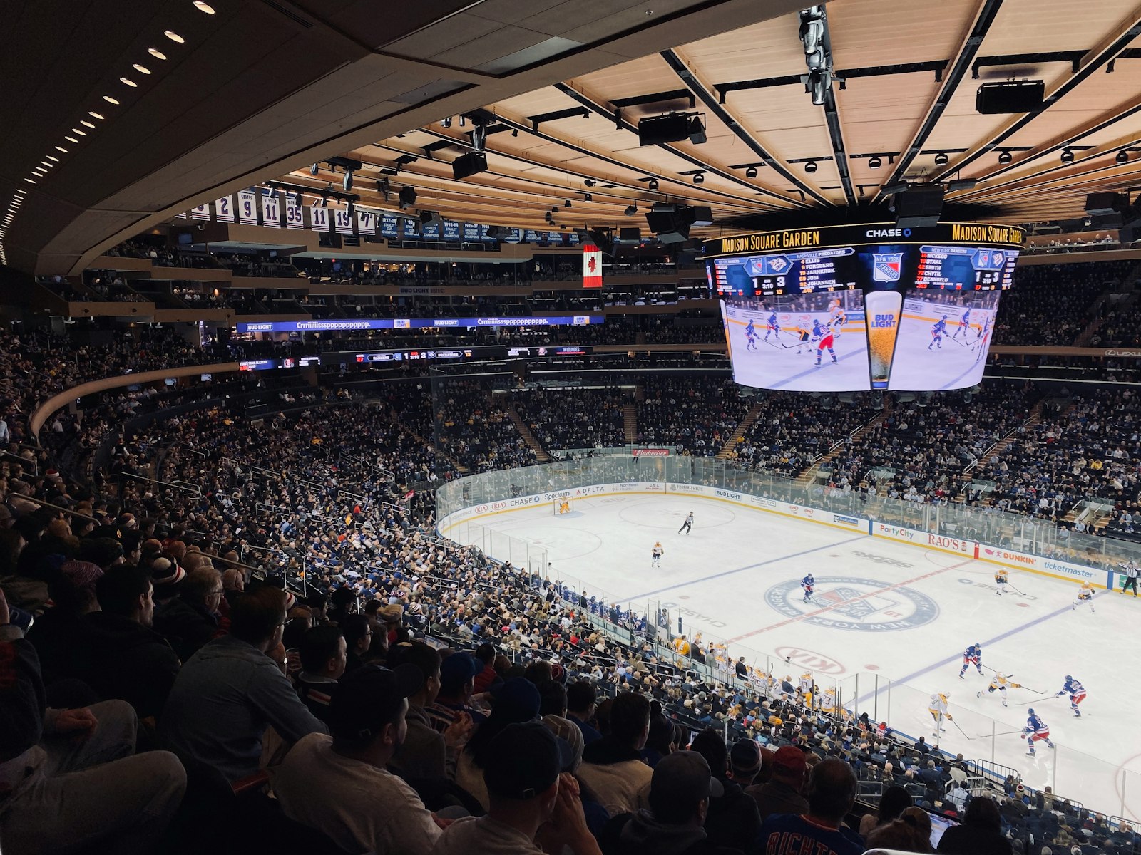 NHL game in progress in a packed arena seen from the stands
