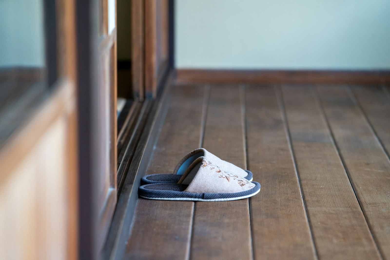 Pair of house slippers resting on a wooden floor by a doorway