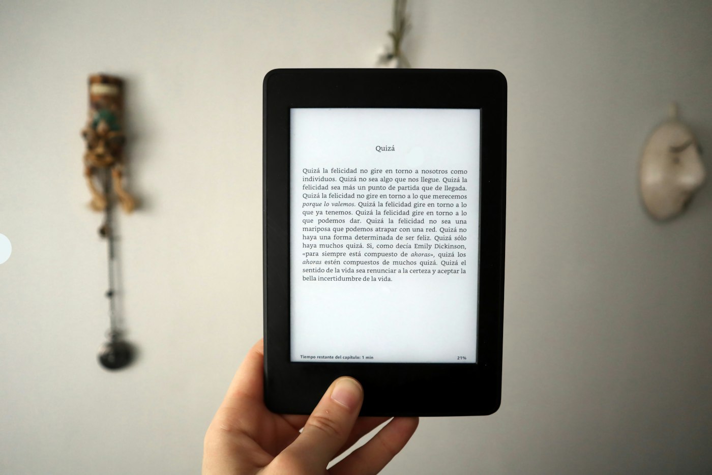 Person holding a Kindle Paperwhite e-reader up against a wall