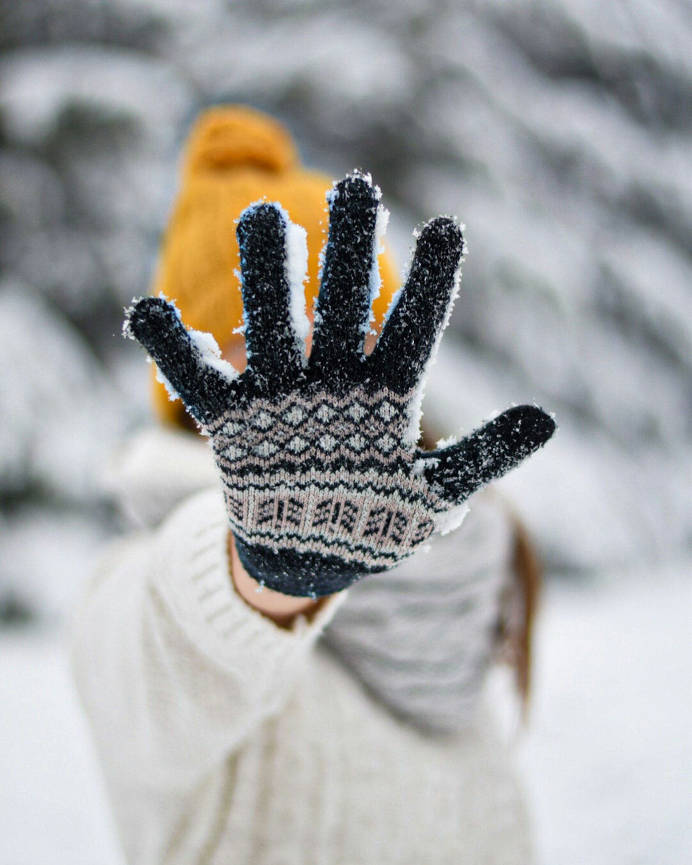 Person wearing white and black knit winter gloves