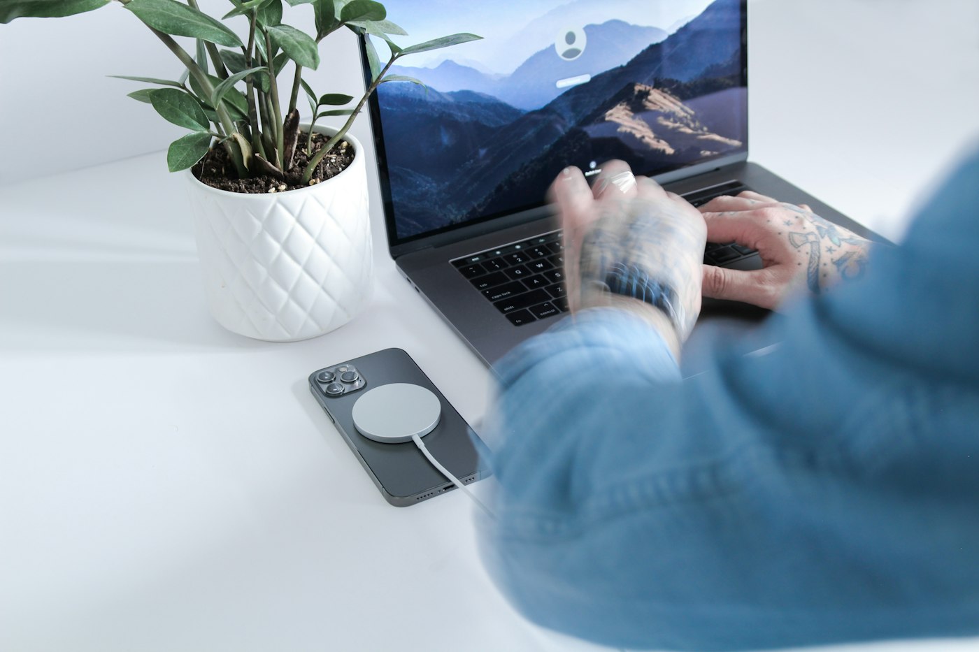 Person in a blue shirt typing on a MacBook