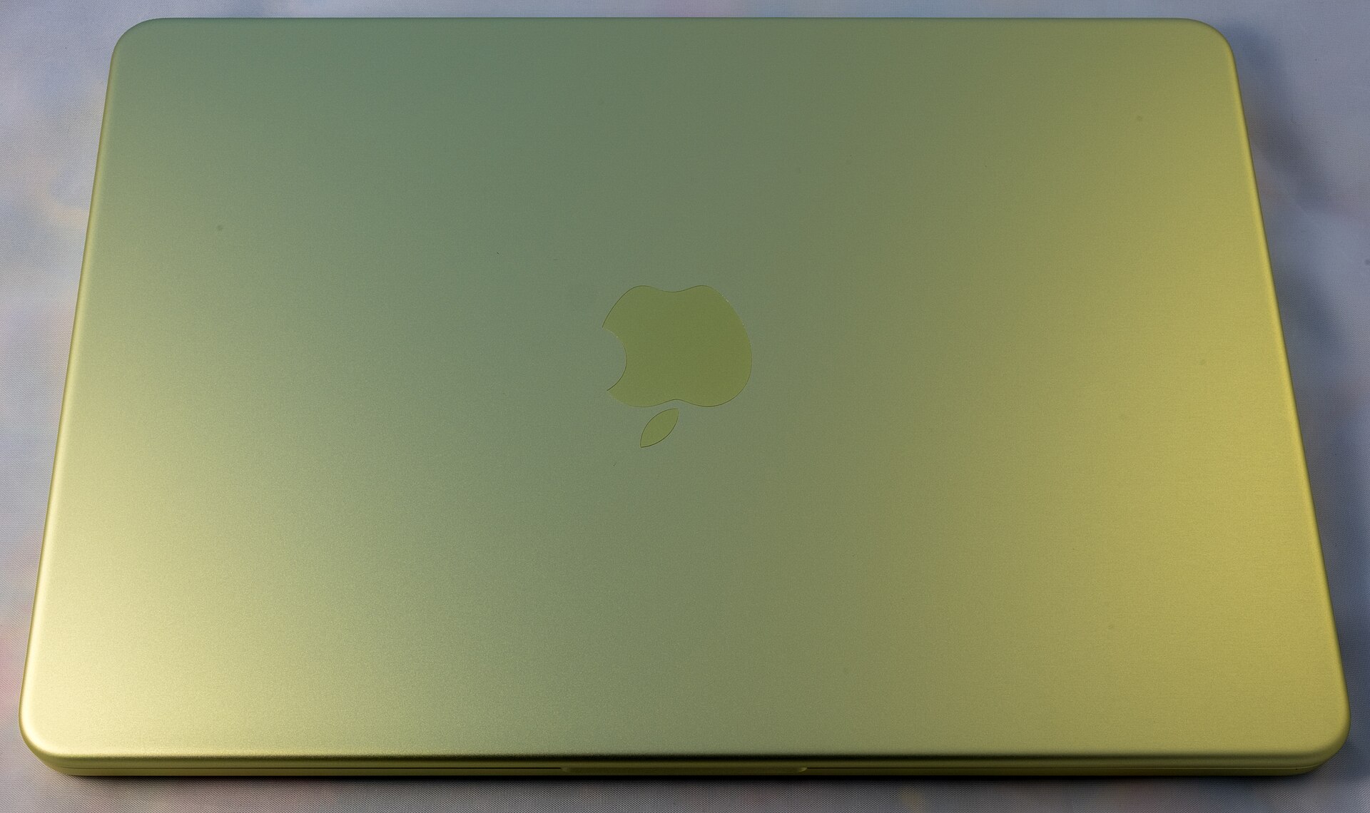 Apple MacBook Neo laptop in the Citrus colour, open on a table
