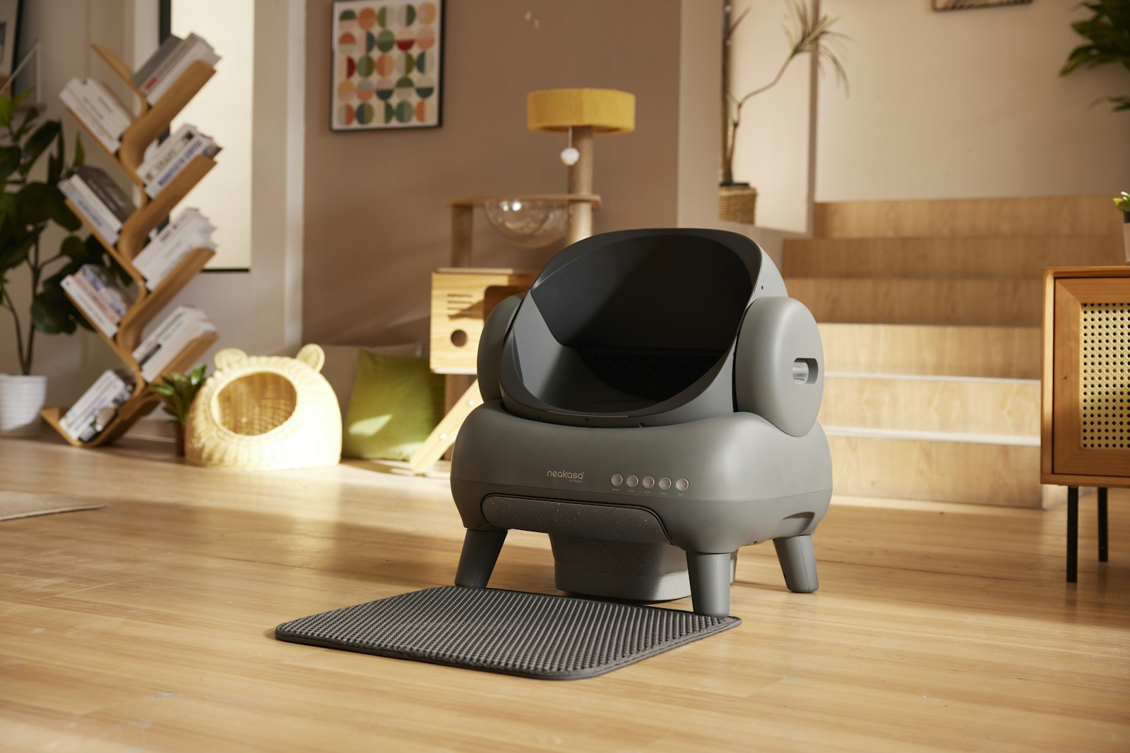 Grey Neakasa open-top automatic litter box with a litter mat in a bright living room