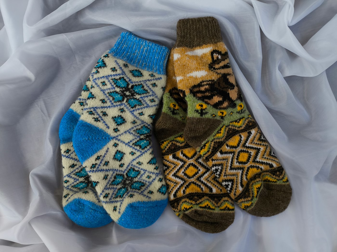 Three pairs of patterned socks laid flat on a white sheet