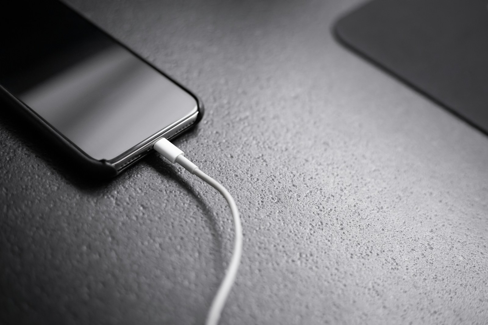 Smartphone charging on a desk with a white USB cable