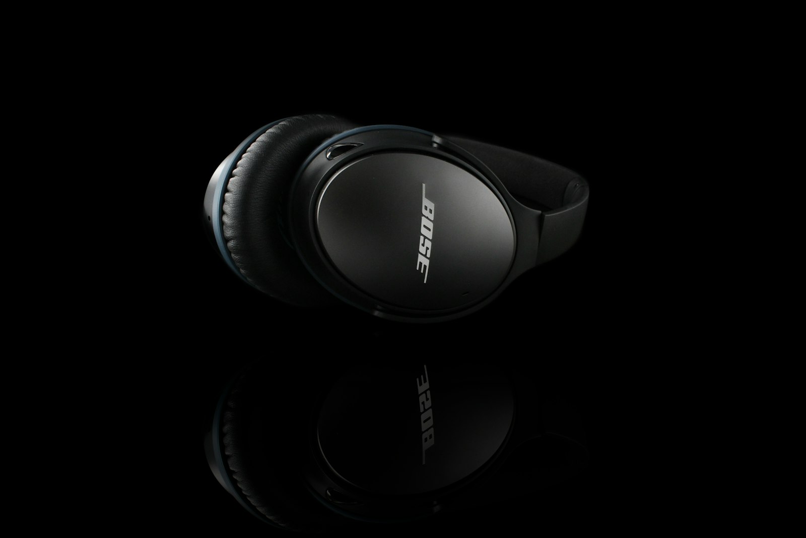 Black Bose over-ear noise-cancelling headphones on a dark reflective surface