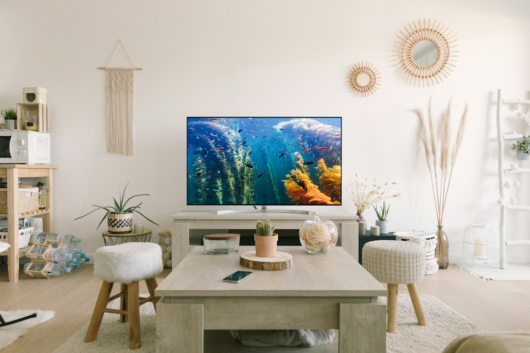 Flat-screen TV turned on beside a white wooden table