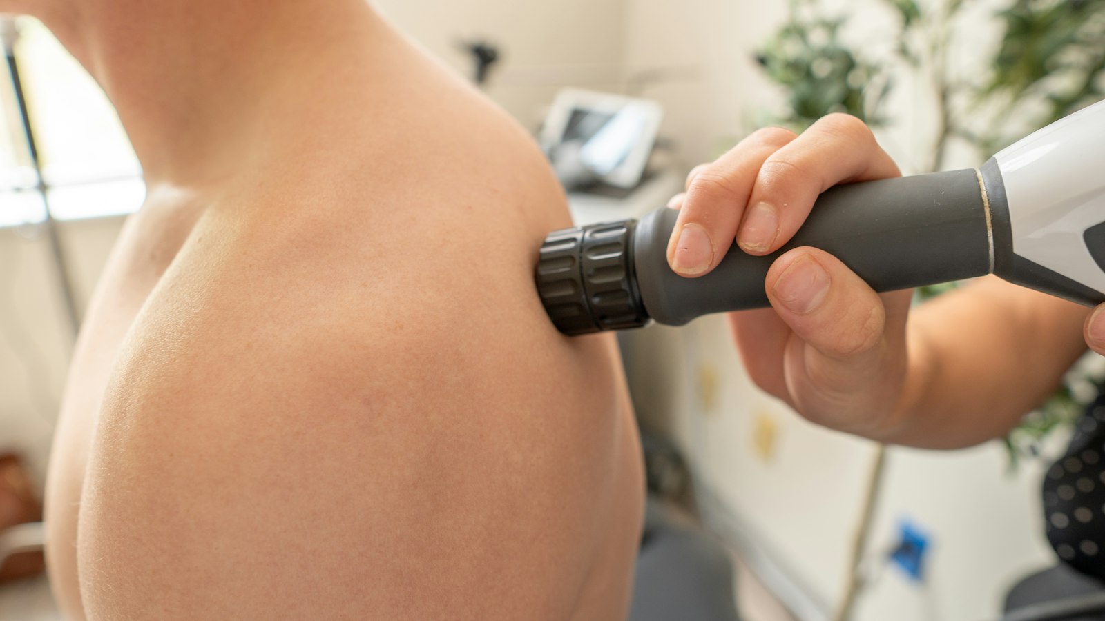 Patient receiving shockwave therapy on the shoulder from a practitioner