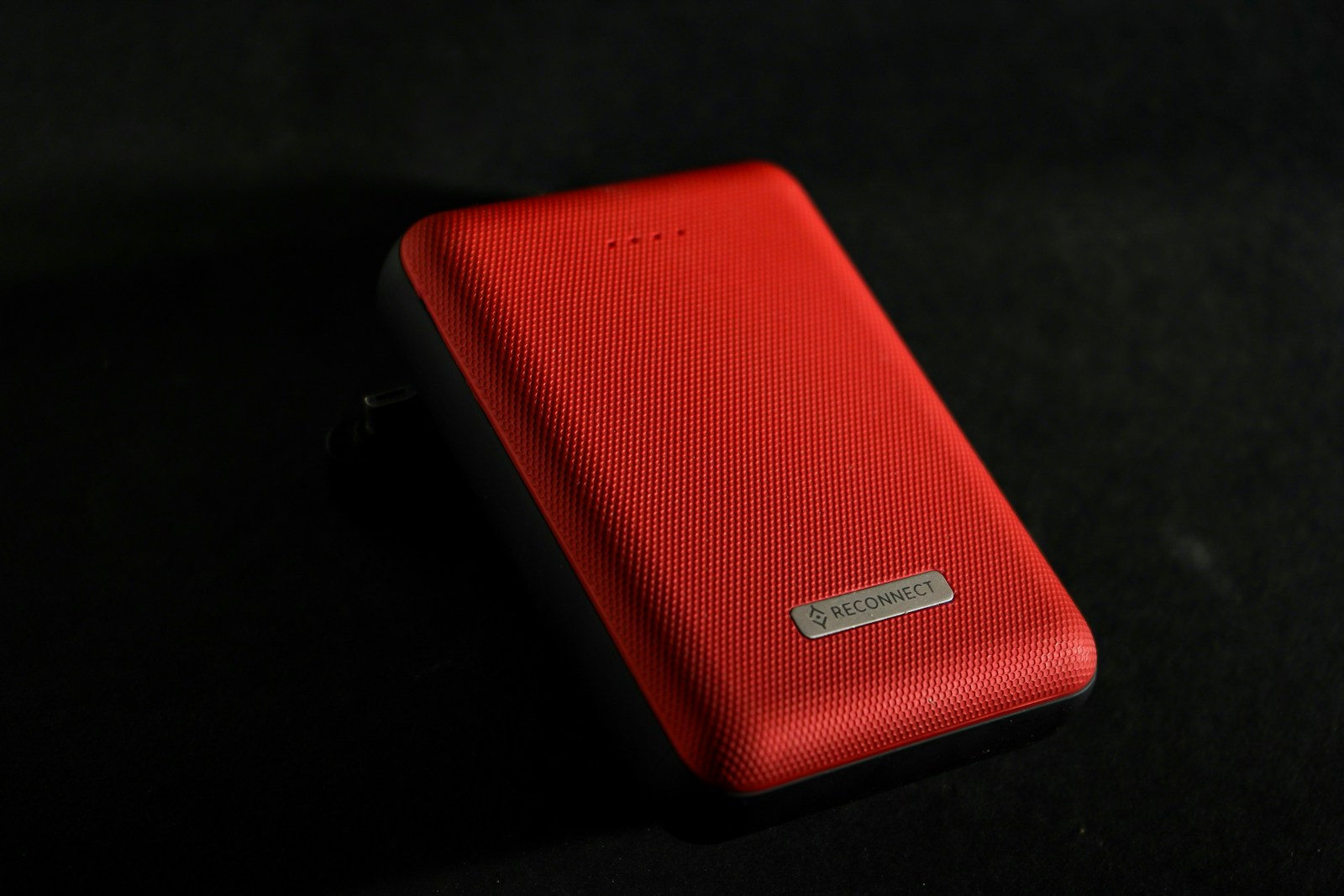 A red portable power bank on a dark surface
