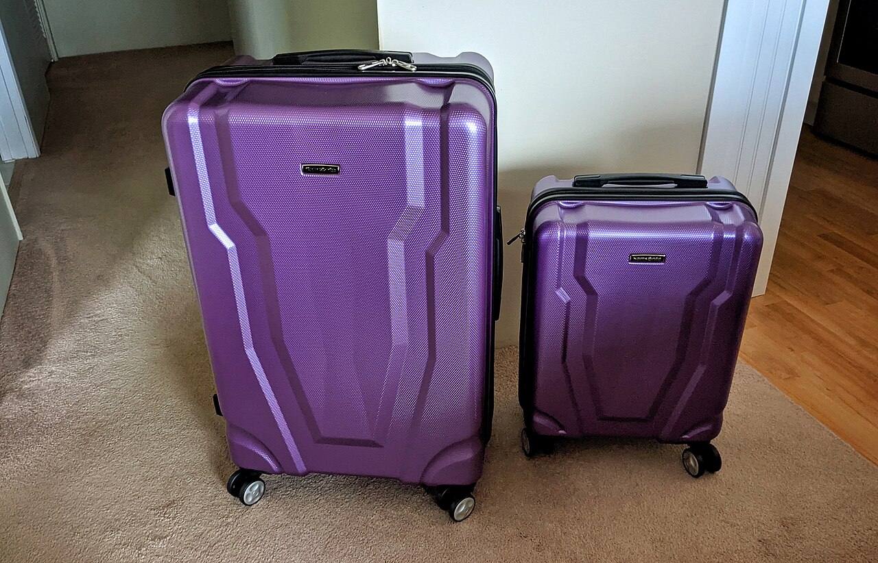 Two purple Samsonite hardside spinner suitcases, a large checked size beside a smaller carry-on size
