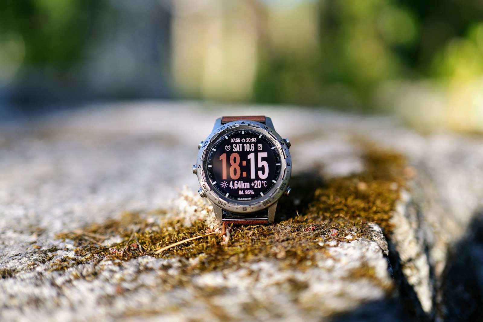 Smartwatch displaying the time on a mossy surface outdoors