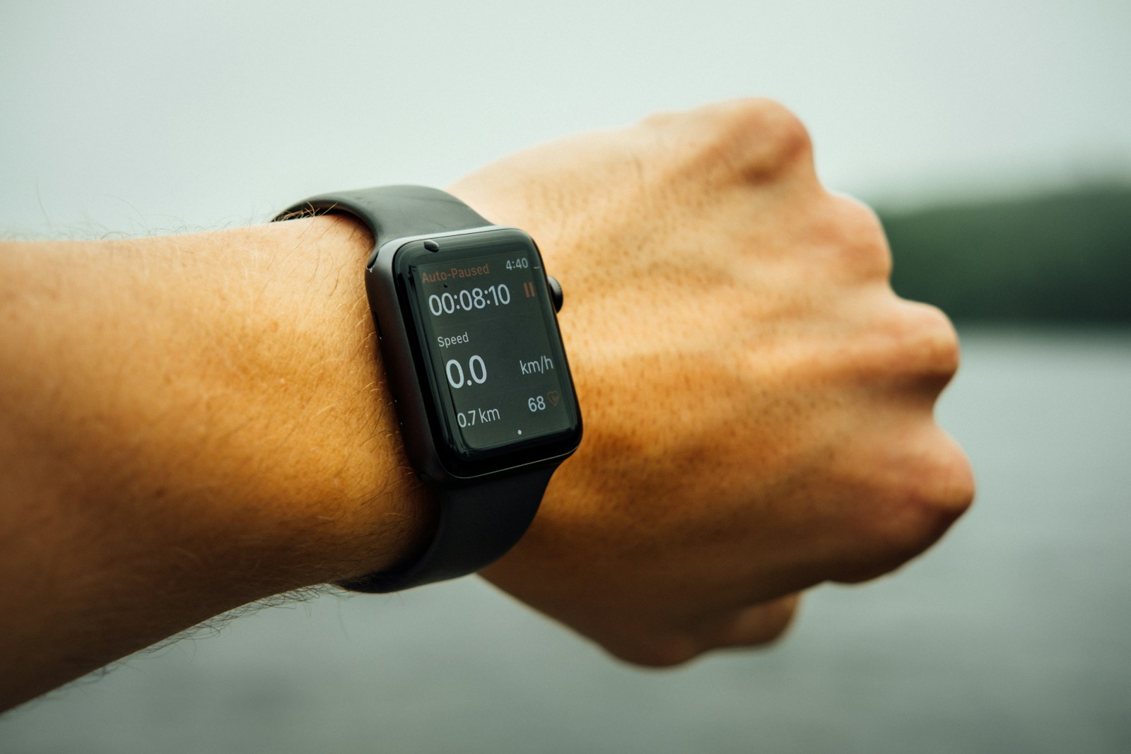 Runner's wrist wearing a black smartwatch showing elapsed time and speed during a workout
