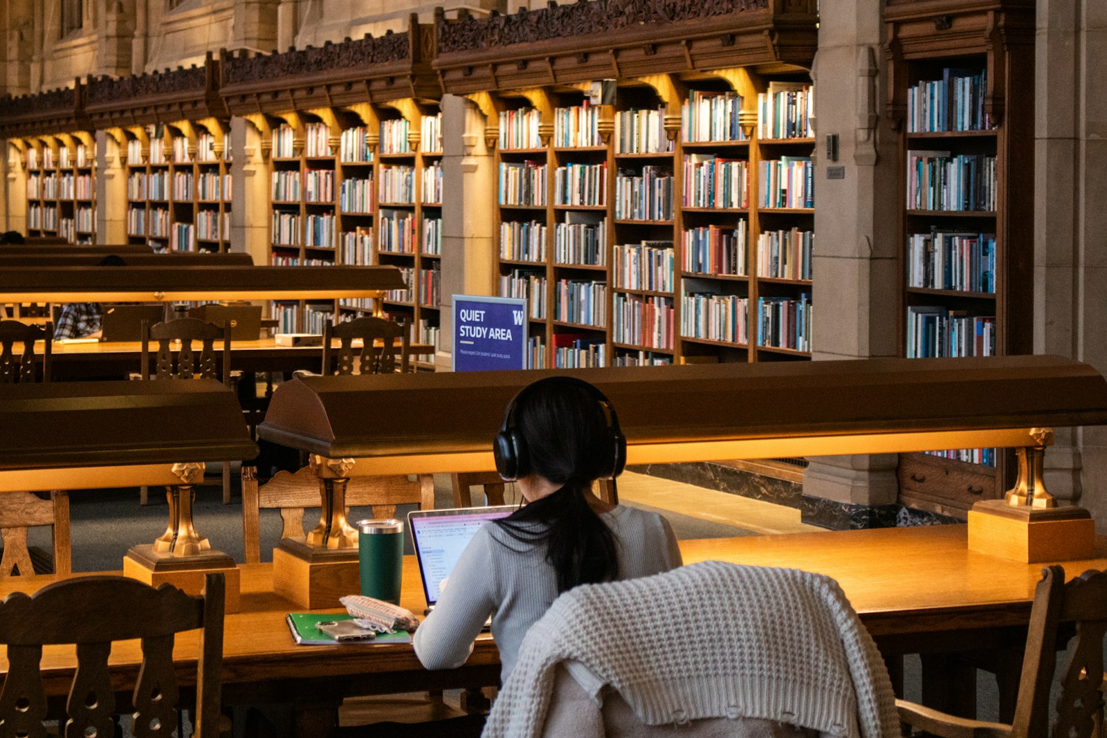 A student works on a laptop in a university library reading room