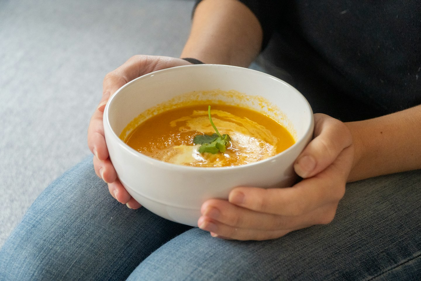 Person holding a bowl of creamy pumpkin soup, a recipe a Vitamix can heat by blade friction