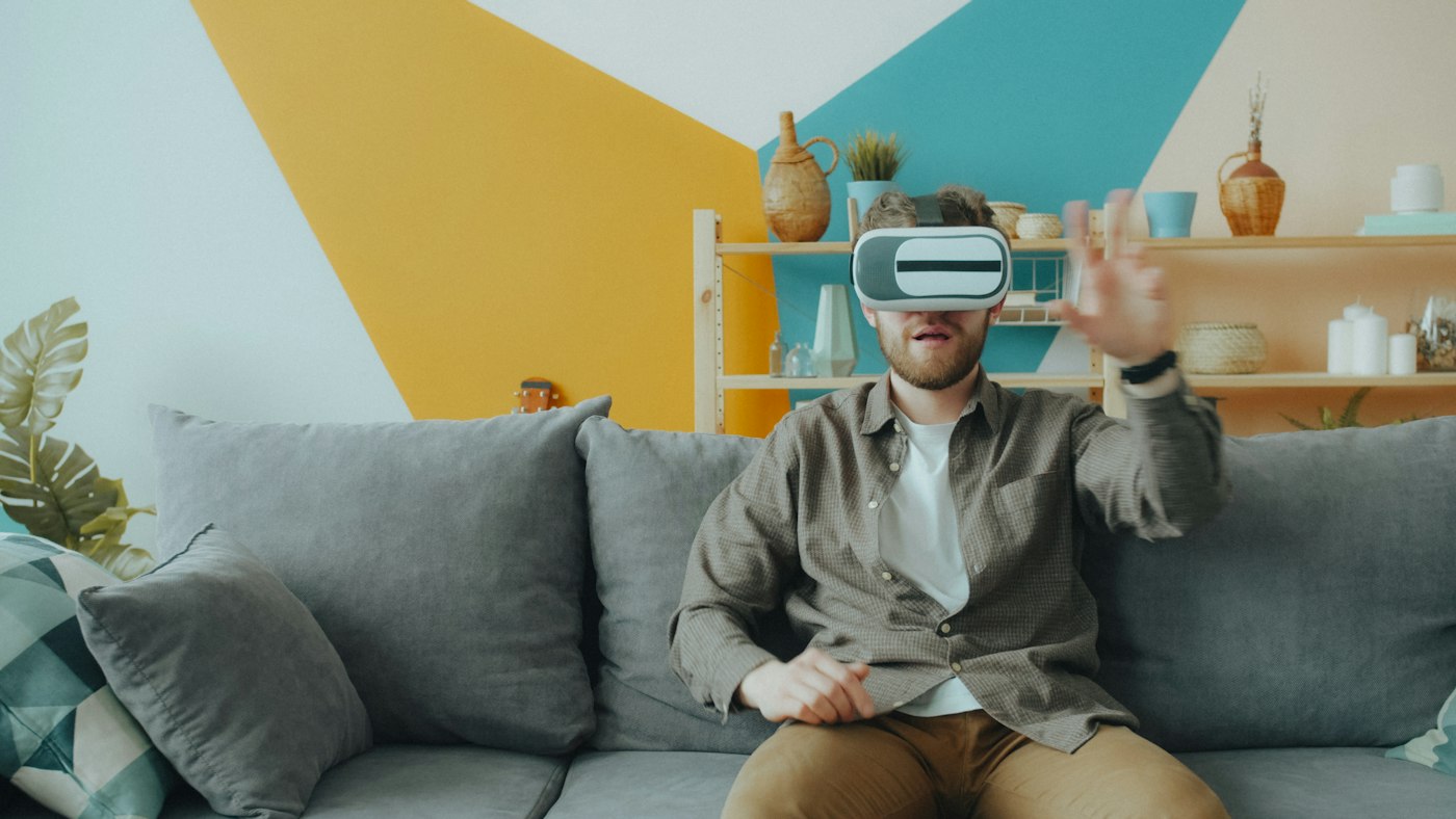 Man playing a game in a VR headset on a sofa at home