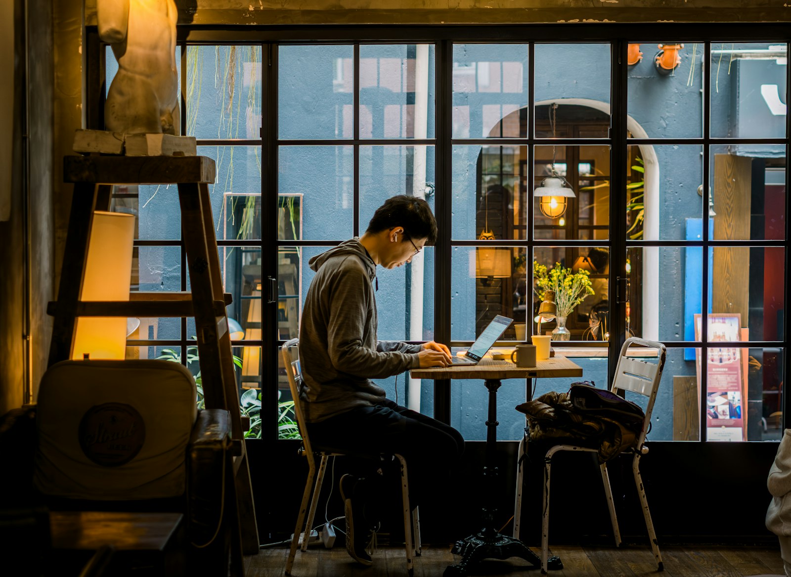 A man working on a laptop in a cafe by the window